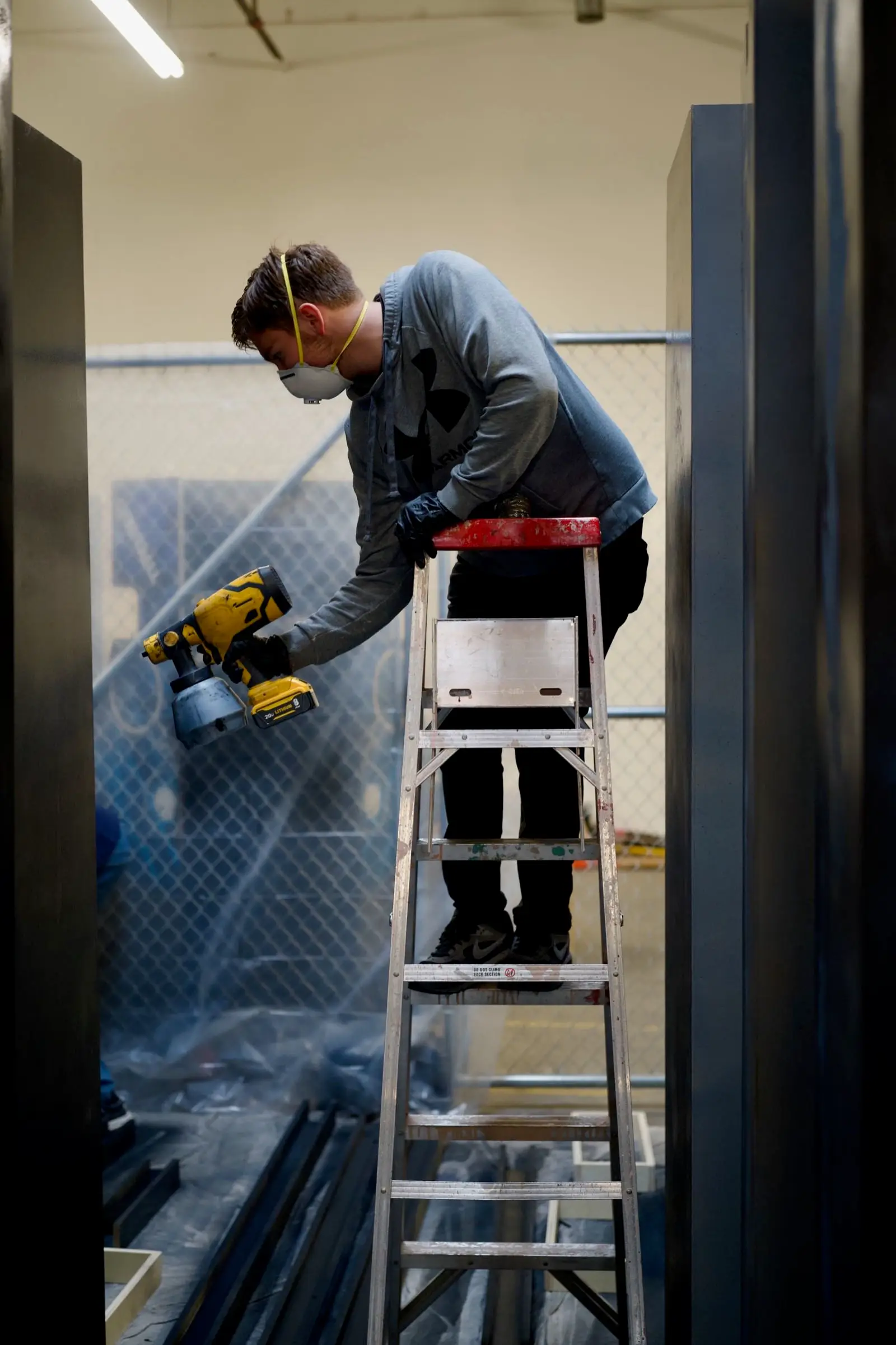 Crew painting stage panels on ladder